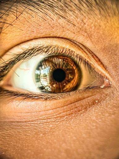 A macro shot of a human  light brown eye, with a soft focus and blurred background