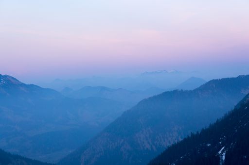 A breathtaking aerial shot of mountains during daytime under a pastel sky