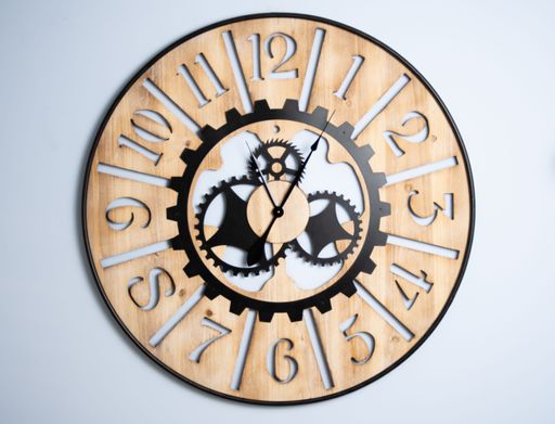 A closeup of an antique-style wooden clock on a white wall