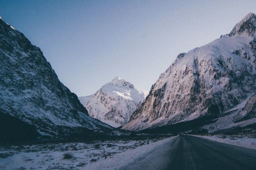 A beautiful shot of an empty road going through high rocky mountains covered with snow
