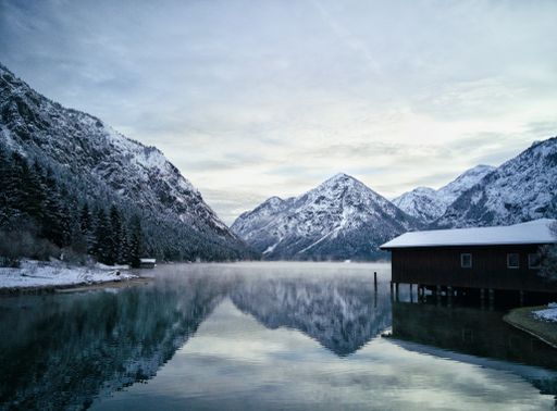 A residence house near the lake surrounded by beautiful rocky mountains covered with snow