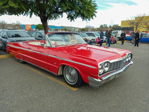 old red 1964 Chevrolet Chevy Impala SS Super Sport V8 two door convertible by GM in a parking lot. Classic car show
