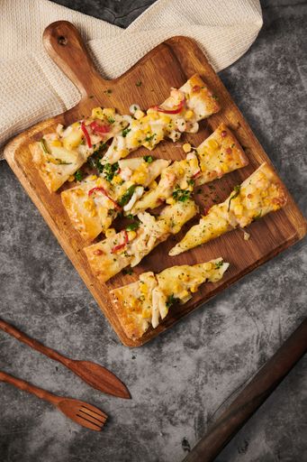 A vertical top view of delicious pizza served on a wooden board