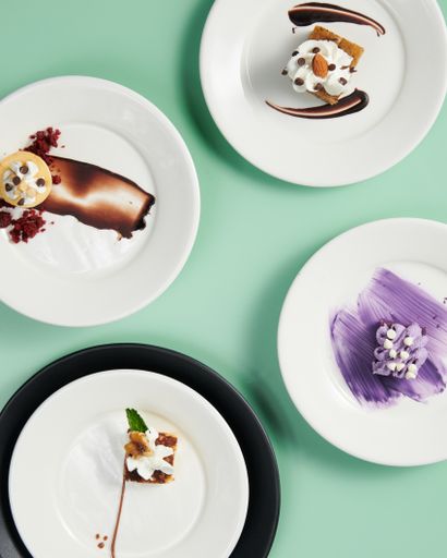 A vertical top view of small cakles served on decorated plates on a minty background