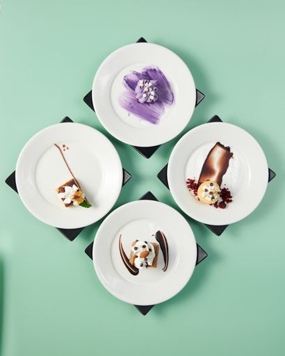 A vertical top view of small cakes served on decorated plates on a minty background