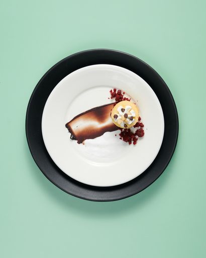 A vertical top view of a small cake served on a decorated plate on a minty background