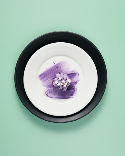 A vertical top view of a small cake served on a decorated plate on a minty background