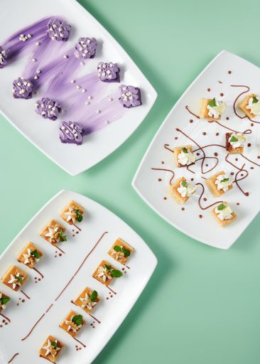 A vertical top view of small cakes served on decorated plates on a minty background