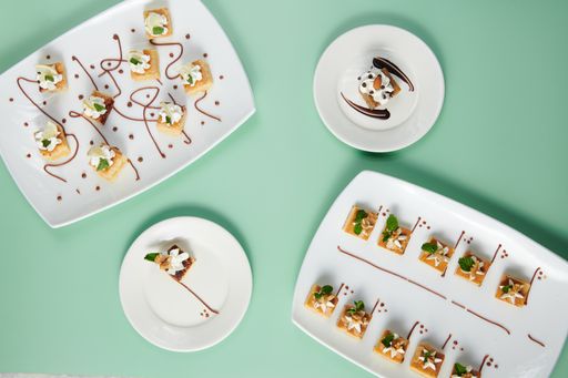 A top view of small cakes served on decorated plates on a minty background