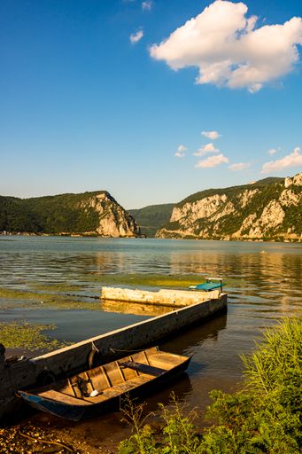 A vertical view of Danube Gorge with a boat and mountain forests under a clear sky