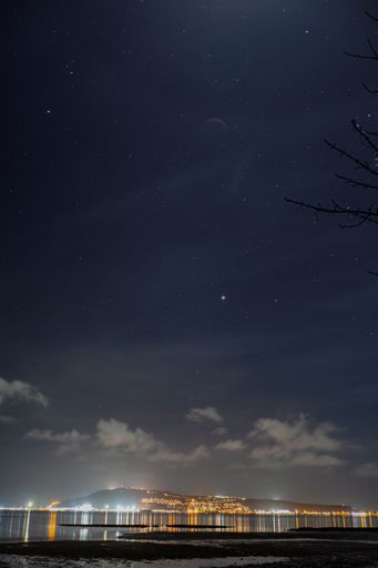 A vertical shot of the night sky and city lights in the distance in Dorset, UK