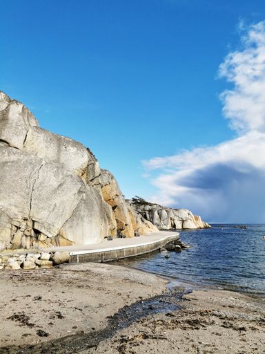 A vertical shot of a sandy beach at Ranvika, Norway, under a bright cloudy sky