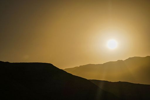 view of Oman's desert landscape at sunset, featuring the silhouettes of distant mountains and a vibrant sky