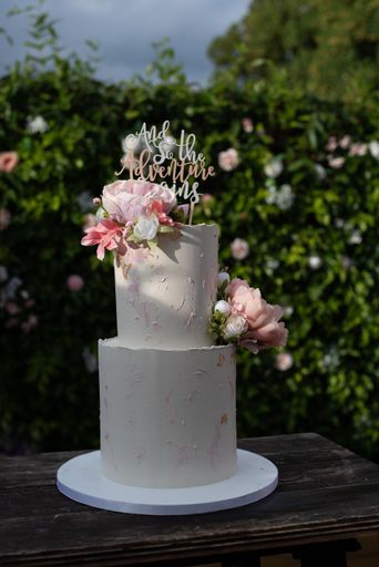 A delectable wedding cake with flowers on an outdoor wooden table