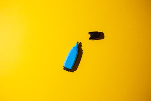 A top view of a blue marker on a yellow work table