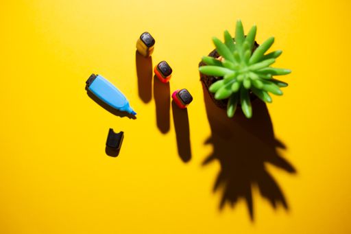A top view of multicolored markers and a plant on a yellow work table