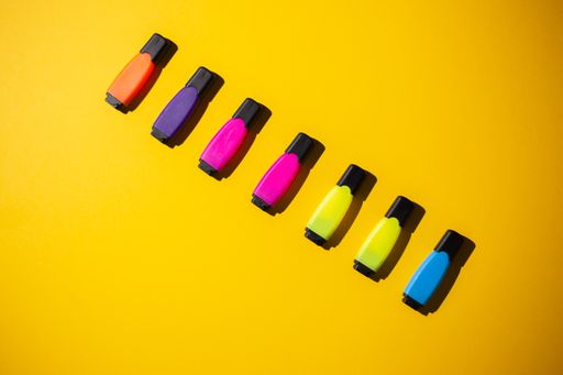 A top view of multicolored markers on a yellow work table