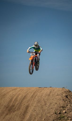 A Man performing an aerial stunt on a motorcycle, silhouetted against a blue sky