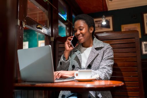 A shallow focus of a young black woman working on her laptop from a coffee shop