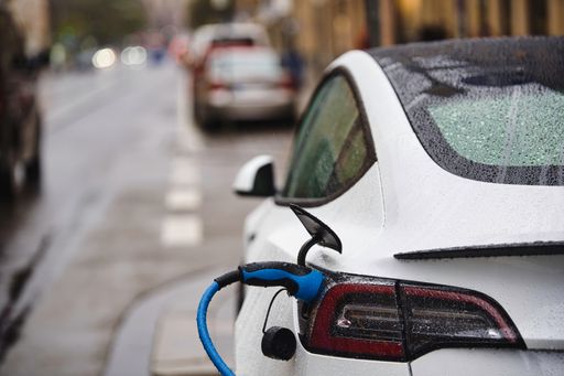 Electric car is connected to the charging station. Electric vehicle standing in the rain in Munich city