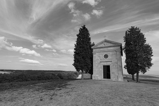 A stunning view of the Cappella della Madonna di Vitaleta in the Tuscan region of Italy, surrounded by rolling hills and lush vegetation