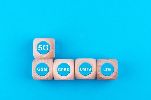 A top view of wooden cubes with 5G and other mobile network technology signs on blue background