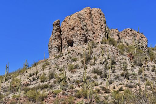 A large rock formation sets high on a hill in the Arizona desert.