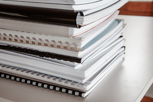 A stack of binded workbooks on a table