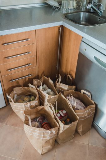 Shopping bags full of products and groceries in the kitchen. Meat, water, eggs, vegetables, milk, fruits
