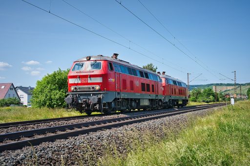 A bright red commuter train travelling down the railroad tracks.