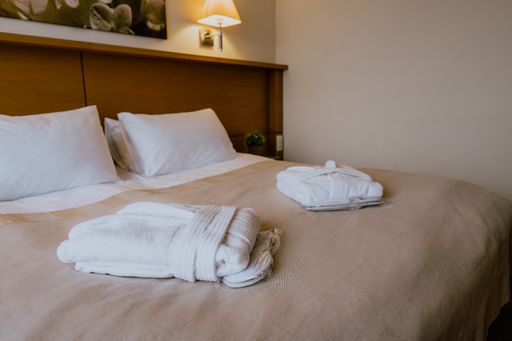 An interior of a simple and nicely furnished cozy hotel room with folded robes on a double bed