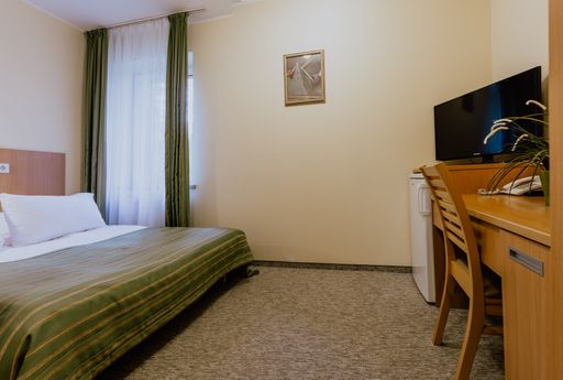 An interior of a simple and nicely furnished cozy hotel room with a double bed during daytime