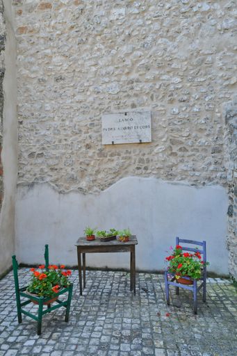 Some chairs adorned with flowers in a narrow street of a medieval village in the province of Rome.