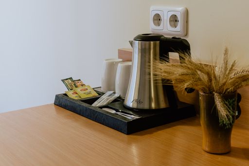 A closeup shot of a tea making set on a wooden table in the hotel room