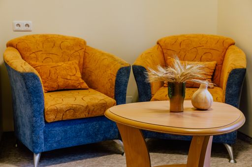 A small corner of a hotel room with two armchairs and an oval wooden table