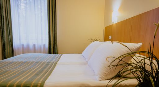 A double bed in a simple and nicely furnished cozy hotel room during daytime