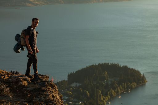 A male hiker standing at the edge of a cliff overlooking the sea