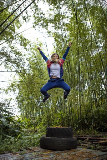 A vertical shot of a Hispanic woman with blonde hair jumping in the air