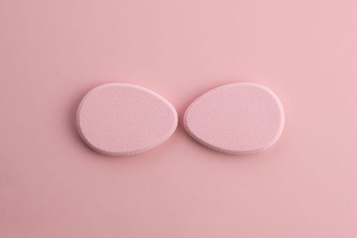 The Cosmetic sponge in the shape of an egg on a pink background. Top view