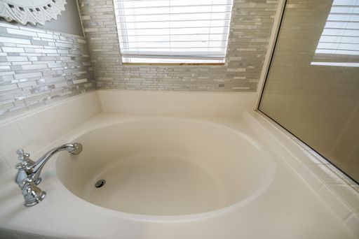 A modern interior of a bathroom with a big bathtub and tiled walls