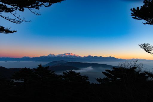 A scenic view of majestic mountains silhouetted against a stunning evening sky, creating an awe-inspiring scene
