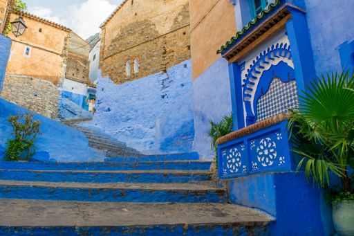 Narrow street with blue painted walls and stairs in the medina of city of Chefchaouen, Morocco.  Very quiet street in the early morning