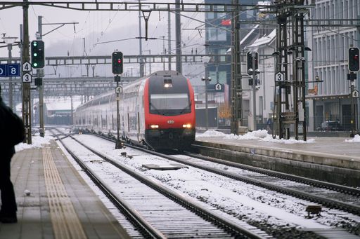 A red train traveling along a snowy railroad in Olten, Switzerland