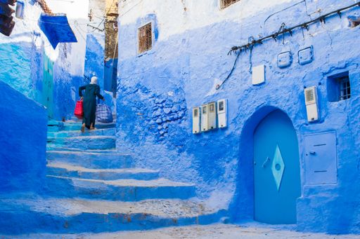 Narrow street with blue painted walls and stairs in the medina of city of Chefchaouen, Morocco.  Very quiet street in the early morning