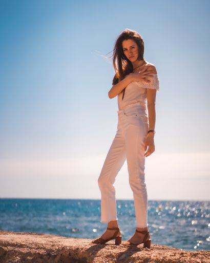 A young attractive woman from Spain dressed in white posing for the camera on the beaches of Calpe, Valencia, Spain