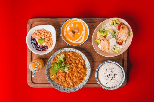 A top view of various dishes on a cutting board on a red background