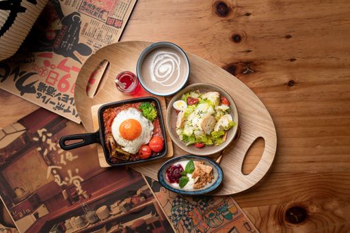 A top-down shot of a breakfast spread featuring eggs, a salad, and a yogurt cup on a wooden table