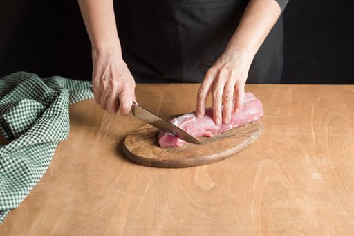 A person slicing pork tenderloin for making a meal