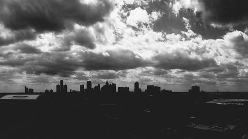 A grayscale shot of cityscape silhouette under the cloudy sky