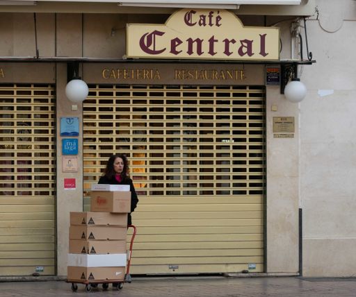 Delivery woman waiting with cardboard boxes in front of a closed restaurant